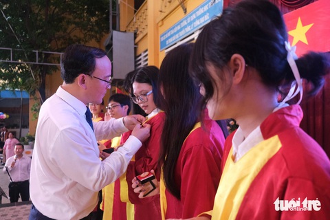 Thầy hiệu trưởng nhắn học sinh hãy 'tự cứu mình như Mị'- Ảnh 2. Các em học sinh nhận huy hiệu trưởng thành từ thầy cô - Ảnh: NGỌC PHƯỢNG