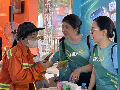 Sinh viên ngành truyền thông thích thú tác nghiệp tại Lễ hội Không tiền mặt- Ảnh 5. Nhân viên ngân hàng tư vấn cho khách giao dịch không tiền mặt lọt vào ống kính sinh viên - Ảnh: BẢO CHÂU