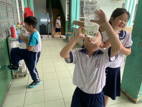 Học sinh một trường tiểu học tại TP.HCM cả năm còng lưng mang nước đến trường- Ảnh 3. Bên trong trường, nhiều học sinh khi ra chơi phải bê những bình nước lớn để tự lấy nước uống - Ảnh: PHCC
