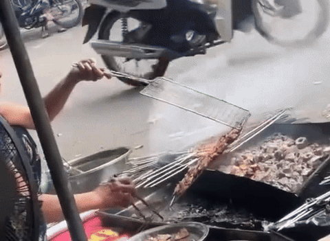 Quán bún chả ở Hà Nội nhúng thịt vào khay nước đen ngòm- Ảnh 1. Hình ảnh người phụ nữ ở quán bún chả nhúng miếng thịt vào khay nước đen - Ảnh: L.T.