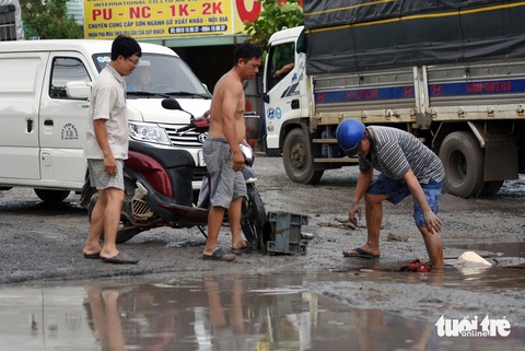 Cận cảnh đường BOT đầy ổ gà, ổ voi, con mương bẫy người đi đường ở Đồng Nai- Ảnh 8. Người dân địa phương hỗ trợ một người đi xe máy sụp ổ gà ngã ra đường