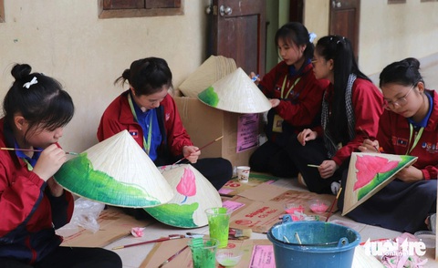 Chiến sĩ tình nguyện hè TP.HCM vẽ phòng học, làm sân chơi cho trẻ em Lào- Ảnh 6. Chiến sĩ Mùa hè xanh tô điểm cho chiếc nón lá bằng những nét cọ tạo thành hình hoa sen - Ảnh: DIỆU QUÍ
