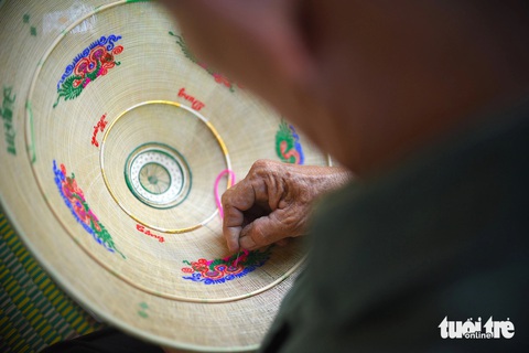 Ông Đặng Văn Lan cẩn thận thêu tay từng đường chỉ theo yêu cầu của khách hàng Ông Đặng Văn Lan cẩn thận thêu tay từng đường chỉ theo yêu cầu của khách hàng