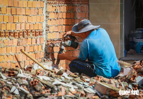 Bà con ở đường Nguyễn Thị Định đồng loạt tháo dỡ nhà, giao mặt bằng mở rộng đường- Ảnh 2. Một bức tường của căn nhà trên đường Nguyễn Thị Định đang được người dân khoan, tháo dỡ - Ảnh: CHÂU TUẤN