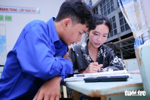 Thí sinh ôn tập nước rút trong đêm trước ngày thi- Ảnh 1. Em Dương Trúc Thư (phải), học sinh Trường THCS - THPT Kpă Klơng, huyện Mang Yang, ôn bài kèm cho bạn là em Sân, người Ba Na - Ảnh: TẤN LỰC