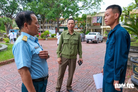 Ảnh: HÀ QUÂN Cán bộ tại đơn vị chiến sĩ Nguyễn Quốc Triệu đóng quân (bìa trái) và cha Triệu nhắc nhở thí sinh về tác phong trước khi đi thi - Ảnh: HÀ QUÂN