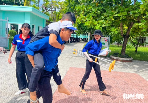 Thí sinh Lê Võ Đình Duy, Trường THPT Quang Trung (Đà Nẵng) bị tai nạn khó di chuyển nên các tình nguyện viên hỗ trợ dìu và cõng Duy vào tận phòng thi - ĐOÀN NHẠN Thí sinh Lê Võ Đình Duy, Trường THPT Quang Trung (Đà Nẵng), bị tai nạn khó di chuyển, nên các tình nguyện viên hỗ trợ dìu và cõng Duy vào phòng thi - Ảnh: ĐOÀN NHẠN