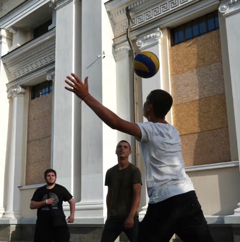 Mặc kệ chiến tranh, người dân Ukraine hòa vào không khí Euro 2024- Ảnh 2. Một nhóm học sinh Ukraine đang hào hứng chơi đá bóng trước Nhà thờ lớn Odessa, Ukraine - Ảnh: RICHARD MORGAN