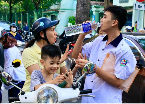 Những cái ôm của mùa thi tốt nghiệp- Ảnh 4. Phụ huynh tiếp nước cho thí sinh chuẩn bị vào thi ba môn tổ hợp - Ảnh: THẢO LINH