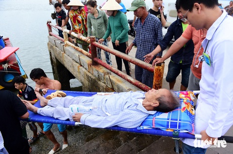 Theo chân một ca cấp cứu từ xã đảo vượt biển vào đất liền- Ảnh 1. Bệnh nhân được y bác sĩ cùng người dân hỗ trợ đưa xuống ca nô để di chuyển vào đất liền