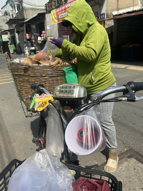 Tiếng loa cầm tay inh ỏi từ sáng đến khuya, từ đường lớn đến hẻm nhỏ- Ảnh 1. Chị Sáu bán bánh mì ở phường Dĩ An (TP Dĩ An, Bình Dương) chạy khắp xóm với chiếc loa cầm tay rao inh ỏi - Ảnh: ĐỊNH DƯƠNG