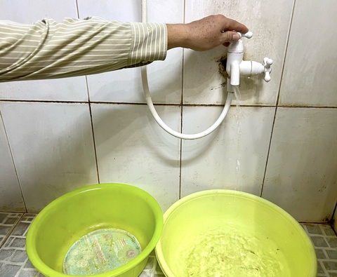 Người dân Sóc Trăng hứng từng xô nước máy giữa mùa mưa- Ảnh 1. Những khi nước chảy yếu, người dân phải hứng vào thau trữ lại để sinh hoạt - Ảnh: KHẮC TÂM