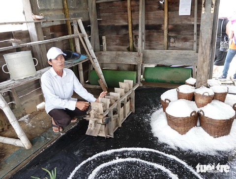 Anh Nguyễn Ngọc Thơ giới thiệu sa quạt chuyển nước từ ô ruộng muối này qua ô kia. Anh Thơ cho biết: xưa kia tát 420 m2 nước làm trong 45 phút, nay chỉ việc cắm điện ngồi hút điếu thuốc là xong - Ảnh: T.T.D. Anh Nguyễn Ngọc Thơ giới thiệu sa quạt bằng tay chuyển nước từ ô ruộng muối này qua ô kia. Anh Thơ cho biết: Xưa kia tát 420m³ nước làm trong 45 phút, nay chỉ việc cắm điện ngồi hút điếu thuốc là xong - Ảnh: T.T.D.