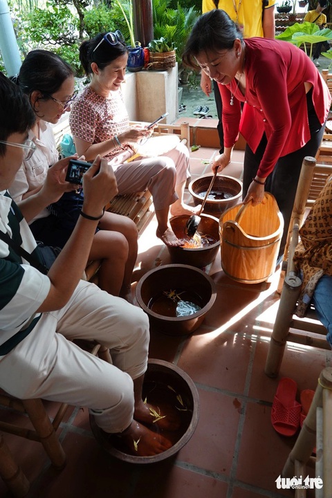 Chị Năm Tuyết phục vụ khách ngâm chân bằng thảo dược và muối Thiềng Liền - Ảnh: T.T.D. Chị Năm Tuyết phục vụ khách ngâm chân bằng thảo dược và muối Thiềng Liềng - Ảnh: T.T.D.