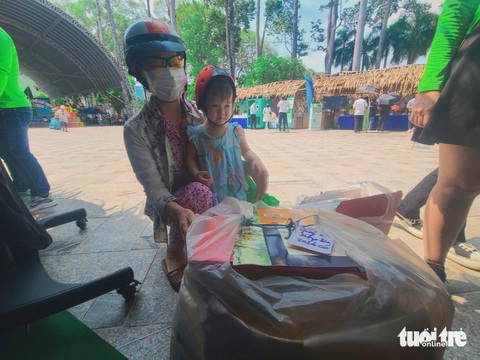 Người dân hào hứng đem quần áo cũ, pin, chai nhựa... đổi quà tại Ngày hội Sống xanh- Ảnh 2. Bà Hoàng Châu (66 tuổi, ngụ quận 12) mang gần 30kg bìa giấy, quần áo cũ... cùng cháu gái tham gia Ngày hội Sống xanh - Ảnh: NHẬT XUÂN