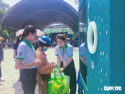 Người dân hào hứng đem quần áo cũ, pin, chai nhựa... đổi quà tại Ngày hội Sống xanh- Ảnh 3. Người dân hào hứng trải nghiệm sử dụng máy thu gom - xử lý vỏ chai nhựa tự động và đổi vỏ chai lấy quà - Ảnh: NHẬT XUÂN