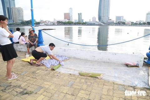 Bờ sông Hàn nhộn nhịp, người dân tới sớm 5 tiếng 'xí' chỗ xem pháo hoa quốc tế- Ảnh 3. Tranh thủ trải bạt xí phần bên sông Hàn - Ảnh: ĐOÀN NHẠN