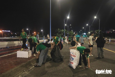 Rác ngổn ngang sau pháo hoa Đà Nẵng, bao giờ hết cảnh người xả người đi dọn?- Ảnh 1. Các nhóm bạn trẻ và du khách xúm nhau nhặt sạch rác trên cầu Sông Hàn sau lễ hội pháo hoa - Ảnh: THANH NGUYÊN