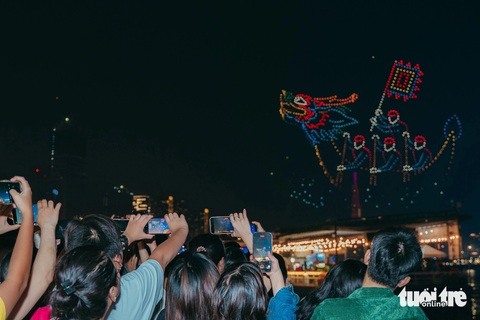Người dân chen kín bờ sông Sài Gòn ngắm 1.100 drone thắp sáng bầu trời- Ảnh 13. Người dân cố gắng lưu lại những khoảnh khắc đẹp của màn trình diễn - Ảnh: THANH HIỆP