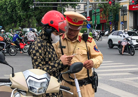 Hà Nội: Người vi phạm giao thông bị thu giấy tờ qua app VNeID- Ảnh 1. Cảnh sát giao thông hướng dẫn người vi phạm xuất trình giấy tờ qua ứng dụng VNeID sáng 1-7 - Ảnh: H.D.