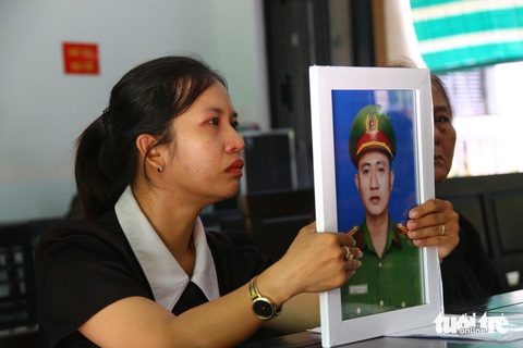 Người đàn ông đâm chết phó trưởng công an phường lãnh 20 năm tù- Ảnh 3. Chị Kim Anh - vợ của trung tá Trần Duy Hùng (phó trưởng Công an phường Thủy Vân) - đem di ảnh chồng đến tòa - Ảnh: NHẬT LINH