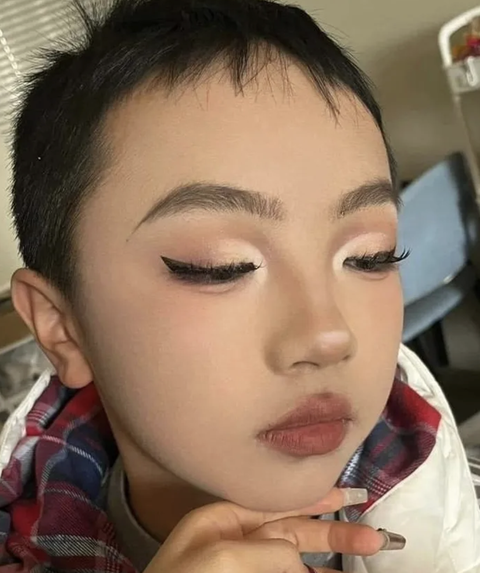Chị gái lôi em trai ra thực hành makeup, kết quả 'lác mắt'- Ảnh 3. Tiếp đó, người chị nhấn nhá đôi mắt hơi buồn của cậu bé bằng hàng mi dày và mắt mèo sắc lẹm.