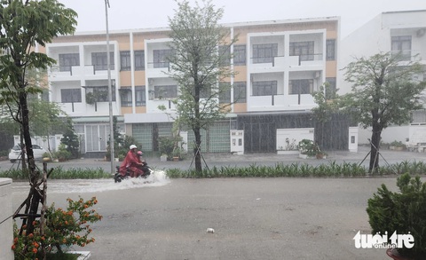 Nhiều tuyến đường biến thành sông ở Rạch Giá- Ảnh 2. Người mẹ chở con đi sáng sớm 11-7 trong cơn mưa tầm tã - Ảnh: BỬU ĐẤU