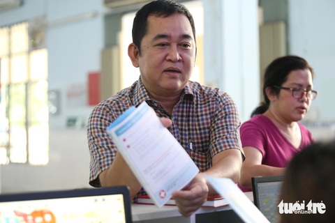 Người dân đi tiêm vắc xin bạch hầu tăng đột biến, Viện Pasteur TP.HCM thông báo 'tạm hết'- Ảnh 4. Bác sĩ Đinh Văn Thới, trưởng phòng khám tiêm chủng (Viện Pasteur TP.HCM), hướng dẫn người dân tìm hiểu cập nhật thông tin về vắc xin - Ảnh: TIẾN QUỐC