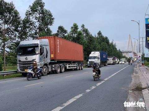 Tiếp tục cấm xe 3 trục qua cầu Rạch Miễu đến khi có cầu Rạch Miễu 2- Ảnh 1. Xe tải, xe container đậu tại một đoạn đường dẫn lên cầu, phía tỉnh Tiền Giang chờ hết giờ cấm để qua cầu - Ảnh: MẬU TRƯỜNG