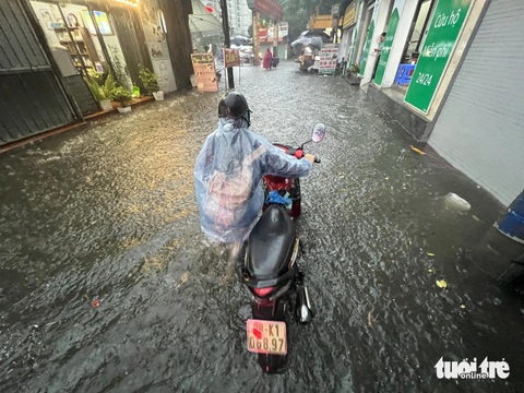 Mưa lớn, nhiều đường phố Hà Nội ngập lút bánh xe- Ảnh 2. Vừa dắt xe ra khỏi ngõ, một chủ xe đã phải dắt bộ vì xe chết máy do ngập úng - Ảnh: PHẠM TUẤN