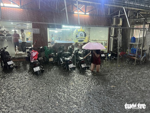 Mưa lớn, nhiều đường phố Hà Nội ngập lút bánh xe- Ảnh 6. Xe máy bị ngập sâu khi dựng trước một quán bi da trên phố Xuân Đỉnh - Ảnh: PHẠM TUẤN
