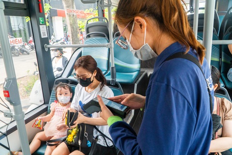 Hà Nội chuyển 100% xe buýt sang buýt điện: Khó hay dễ?- Ảnh 1. Nhân viên một hãng xe buýt điện đang hoạt động tại Hà Nội thu tiền, bán vé bằng máy in vé tự động - Ảnh: PHẠM TUẤN