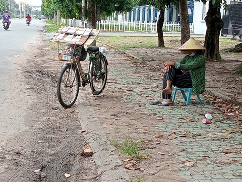 Những giấc ngủ trưa vội vã bên đường- Ảnh 3. Bà Năm bán vé số thường xuyên ngủ ngồi trên đường Nguyễn Trãi, Dĩ An, Bình Dương - Ảnh: ĐỊNH DƯƠNG