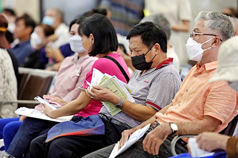 Có hồ sơ sức khỏe điện tử, sổ khám bệnh còn cần không?- Ảnh 5. Bệnh nhân chờ khám bệnh với xấp sổ trong tay - Ảnh: PHƯƠNG QUYÊN