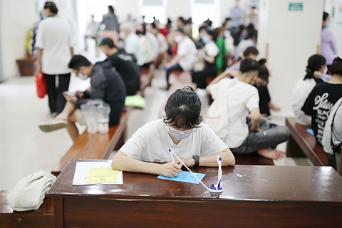 Có hồ sơ sức khỏe điện tử, sổ khám bệnh còn cần không?- Ảnh 3. Bệnh nhân điền thông tin vào sổ khám bệnh tại bệnh viện chiều 11-7 - Ảnh: PHƯƠNG QUYÊN