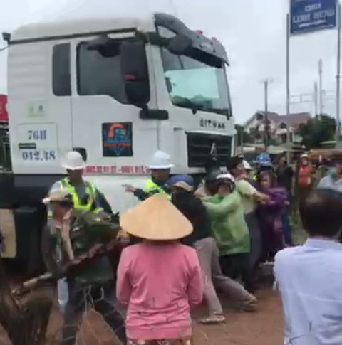 Dân chặn xe chở cánh quạt vào nhà máy điện gió để đòi đền bù- Ảnh 1. Người dân và công nhân nhà máy giằng co trước đầu xe tải chở cánh quạt vào nhà máy điện gió ngày 13-7 - Ảnh cắt từ clip