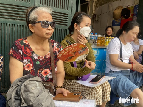 Học sinh giỏi 4 năm vẫn trượt lớp 10 công lập Hà Nội, phụ huynh mang hồ sơ đi nộp tràn tuyến- Ảnh 3. Bà Hoàng Thị Nga (quận Hoàng Mai) cùng nhiều phụ huynh ngồi chờ đợi trường mở cổng để xin vào nộp hồ sơ trực tiếp
