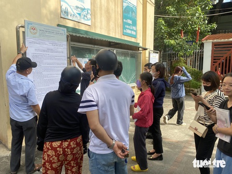 Học sinh giỏi 4 năm vẫn trượt lớp 10 công lập Hà Nội, phụ huynh mang hồ sơ đi nộp tràn tuyến- Ảnh 4. Phụ huynh đọc thông báo của nhà trường về việc đăng ký và xét tuyển bổ sung theo hình thức trực tuyến