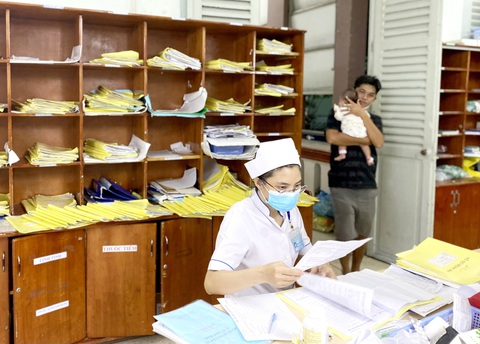 Lộ trình triển khai sổ sức khỏe điện tử đến đâu?- Ảnh 1. Nhân viên y tế Bệnh viện Nhi đồng 2 (TP.HCM) xử lý hồ sơ bệnh án giấy của bệnh nhi - Ảnh: X.MAI