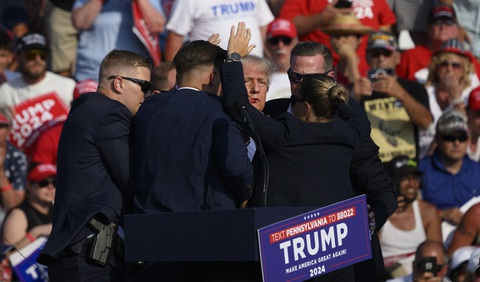 Những khoảnh khắc 'rất Trump' trong vụ ám sát bất thành- Ảnh 5. Máu chảy trên gương mặt của ứng cử viên đến từ Đảng Cộng hòa sau khi bị đạn sượt qua trong vụ việc mà Cục Điều tra Liên bang Mỹ (FBI) xác nhận là âm mưu ám sát. Tuy nhiên may mắn là ông Trump không bị thương nghiêm trọng. Trong ảnh, các mật vụ Mỹ đã lấy thân người che chắn cho ứng viên tổng thống của Đảng Cộng hòa sau khi ông bị bắn trúng tai - Ảnh: AFP
