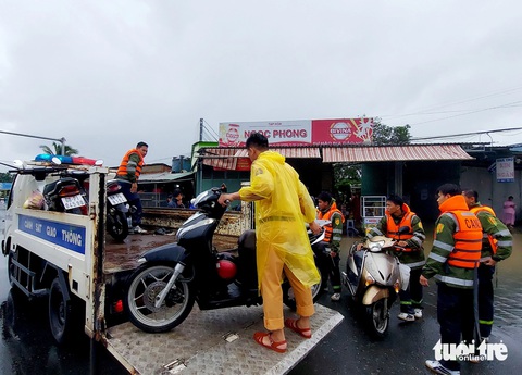 Mưa 2 ngày gây ngập cục bộ, người dân Phú Quốc đi lại khó khăn- Ảnh 6. Hơn 60 cán bộ, chiến sĩ công an và lực lượng chức năng địa phương hỗ trợ vận chuyển xe cho người dân về nhà - Ảnh: CHÍ CÔNG
