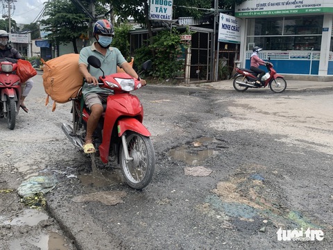 Người dân chật vật với những tuyến đường xuống cấp, chi chít Người dân phải đi sát lề đường trên đường Phạm Văn Sáng (xã Vĩnh Lộc A, huyện Bình Chánh) để né tránh những “ổ gà” - Ảnh: KSOR QUÝ