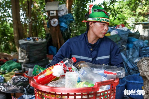 Mưu sinh ở Bà Nguyễn Thị Sơn bê rổ phế liệu đã phân loại rồi cho vào một bao tải mới để bán - Ảnh: HOA NGUYỄN
