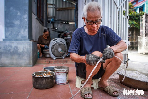 Mưu sinh ở Ông Vương Công Giải, 71 tuổi, đang bóc tách từng sợi dây đèn LED - Ảnh: HOA NGUYỄN