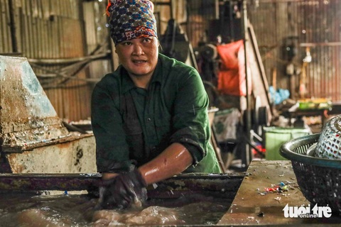 Mưu sinh ở Một công nhân rửa qua tay dưới làn nước đen kịt, bốc mùi ở xưởng xay - Ảnh: HOA NGUYỄN