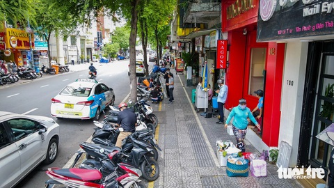 Vỉa hè trung tâm TP.HCM đổi thay ra sao sau 2 tháng thực hiện đề án mới?- Ảnh 3. Vỉa hè được chia làm ba phần, phân biệt bằng màu sơn vạch kẻ. Phía ngoài cùng (sát đường giao thông) rộng khoảng 1m là chỗ để xe máy, chính giữa là lối dành cho người đi bộ khoảng 2m, còn phía trong cùng (sát mặt tiền nhà dân) là khu vực để cho hàng quán thuê làm mặt bằng kinh doanh, buôn bán - Ảnh: CHÂU TUẤN