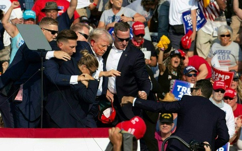 Nhân chứng kể nghi phạm bắn 7 phát đạn, ông Trump may mắn bị đạn sượt qua tai- Ảnh 1. Sau sự cố ngày 13-7, cựu tổng thống Mỹ Donald Trump được mật vụ nhanh chóng hộ tống khỏi hiện trường - Ảnh: AFP