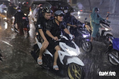 Mưa lớn giờ tan tầm ở TP.HCM, lại điệp khúc 'ngập, kẹt xe'- Ảnh 1. Người dân quên mang áo mưa, đội mưa về nhà sau giờ làm - Ảnh: TIẾN QUỐC