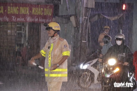 Mưa lớn giờ tan tầm ở TP.HCM, lại điệp khúc 'ngập, kẹt xe'- Ảnh 7. Lực lượng CSGT đội mưa điều phối giao thông tại đường Thống Nhất - Ảnh: TIẾN QUỐC