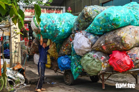 Mưu sinh ở 'thủ phủ' phế liệu ngoại thành Hà Nội- Ảnh 10. Nếu như Quan Độ (Yên Phong, Bắc Ninh) nổi tiếng với việc “mổ xẻ” xác máy móc, thì Xà Cầu lại là “thủ phủ” của rác thải nhựa. Trong ảnh: Một người đàn ông đang chất những bao tải nhựa lên chiếc xe kéo - Ảnh: THÚY TRANG